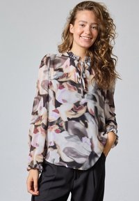 Blomsterbluse i let stof med rynket halsudsk�æring, lange ærmer og elastiske manschetter. Farverne inkluderer blød pink, grå og creme.