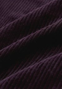 Fialová kordurová tkanina s vertikálnymi žebrovanými líniami, mäkkou textúrou a jemným leskom, ktoré zdôrazňujú hĺbku a trojrozmernosť materiálu.