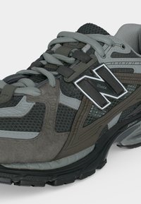 Γκρι και μαύρο αθλητικό παπούτσι New Balance με πάνελ από δίχτυ και σουέντ, με απορροφητική σόλα και λογότυπο "N Lock" στο πλάι.