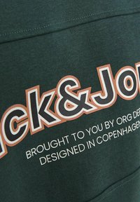 Sudadera verde oscura con el logo de "Jack&Jones" en una fuente blanca y marrón en negrita, con texto adicional debajo en una fuente blanca más pequeña.