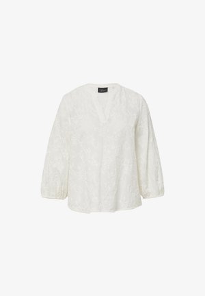 Blouse blanche avec un décolleté en V, des manches trois-quarts et un motif de broderie florale. Le tissu semble léger avec une finition texturée.
