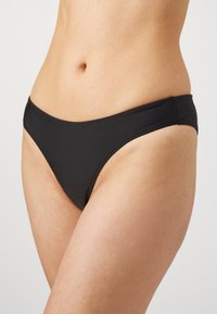 Parte inferior de biquíni preta com um design elegante, feita de um tecido suave e com uma cintura baixa. Apresenta bordas sem costuras, proporcionando um visual minimalista.