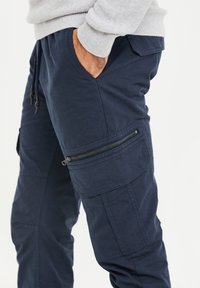 Marineblauwe cargobroek van katoenmix, met zijzakken en een ritszak op de dij voor extra functionaliteit.