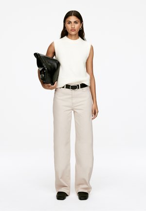 Light gray wide-leg trousers, soft white sleeveless top, black leather clutch bag, and dark shoes. Simple design with minimal hardware.