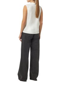 Beżowa top bez rękawów z delikatnym połyskiem, zestawiony z ciemnoszarymi spodniami typu szerokie nogawki z przednimi kieszeniami i bocznymi przeszyciami.