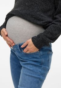 Γκρι, ελαστικό τοπ και μπλε τζιν τζιν. Το τοπ διαθέτει στρογγυλή λαιμόκοψη, ενώ το τζιν έχει κλασική εφαρμογή με πλαϊνές τσέπες.