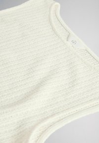 Bílý texturovaný pletený top bez rukávů s kulatým výstřihem a viditelnou štítkem s nápisem "THE SET."