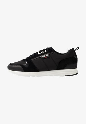 Schwarzer Low-Top-Sneaker mit weißer Sohle, Schnürung vorne und "HUGO"-Logo an der Seitenfläche.