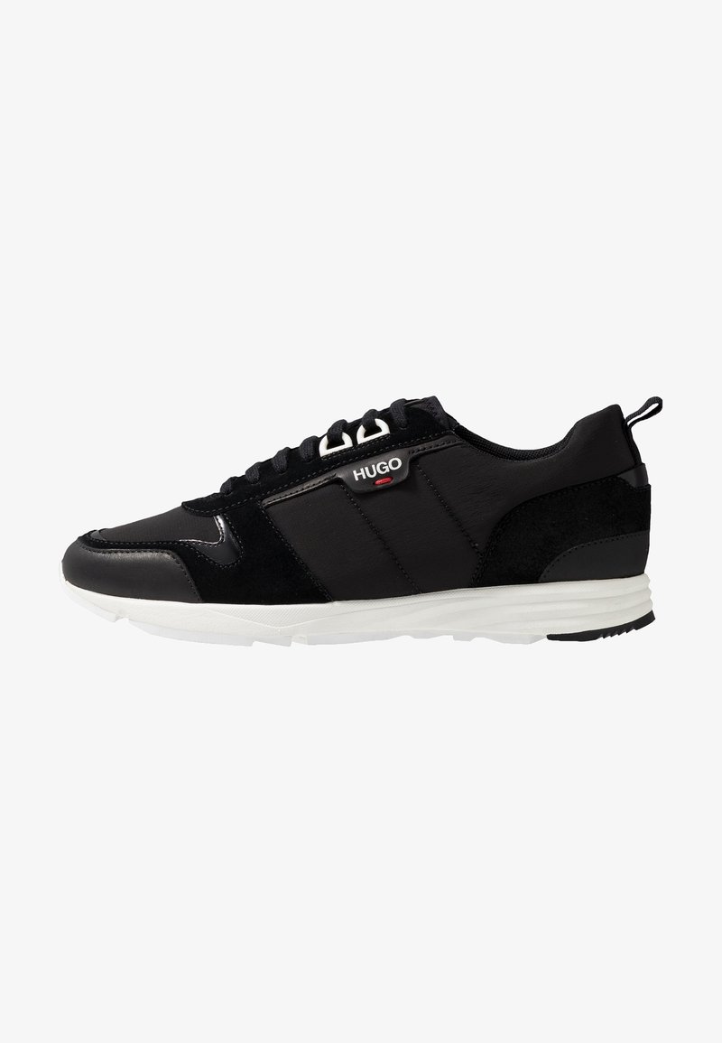Black low-top sneaker with white sole, lace-up front, and "HUGO" logo on side panel.