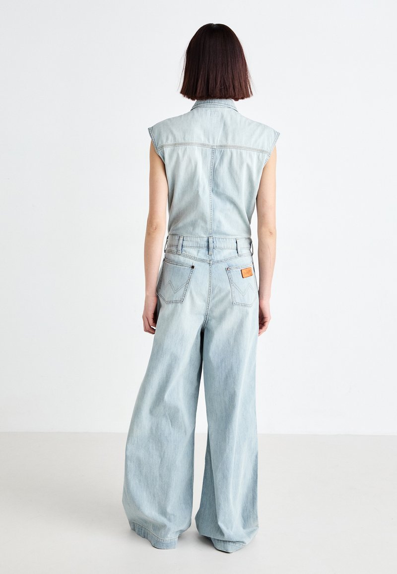 Hellblaues Denim-Overall mit ärmellosem Design, weitem Bein und einem Reißverschluss auf der Rückseite. Verfügt über aufgesetzte Taschen und ein markiertes Lederetikett auf der Rückseite.