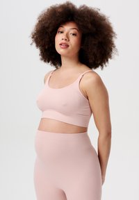 Ljusrosa ribbad graviditets-bra med justerbara band, i kombination med matchande högmidjade leggings som har en sömlös design.