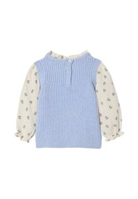 Hellblau gestrickte Weste mit einer strukturierten Oberfläche, darunter eine cremefarbene Bluse, die mit kleinen Blumenmustern und elastischen Bündchen verziert ist.