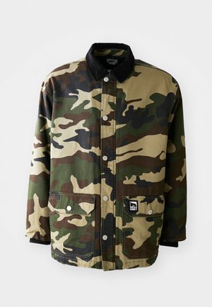 Chaqueta de camuflaje con un cuello de pana negro, botones y dos bolsillos frontales, que presenta una mezcla de patrones de camuflaje en verde, marrón y beige.
