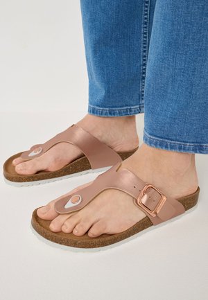 Brown cork sandal with a rose gold leather strap and white sole, featuring a round decorative accent and adjustable buckle.