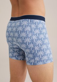 Modre bokserice iz mehkega blaga, z natisnjenim belim vzorcem palm in temnoblazinskim elastičnim pasom.
