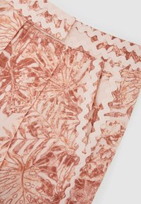 Lähivõte kangast, millel on virsiku ja valge lillemuster, laineline valge ääristus servade ja õmbluste ümber.