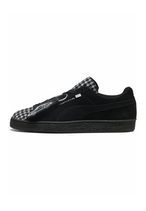 Sort og hvid Porsche x Puma sneaker med ruskindsmateriale og hundetandsmønster på tæer og tunge, vist fra side.