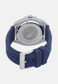 Reloj Nautica con caja de acero inoxidable y una correa de goma azul con un diseño texturizado. Hebilla plateada con el nombre de la marca grabado.