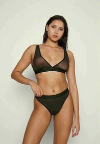 Μαύρο σετ εσώρουχων με διάφανο bralette και σχέδιο v-neck, συνοδευόμενο από κομψά ψηλόμεσα μπικίνι σε απαλή ύφανση.