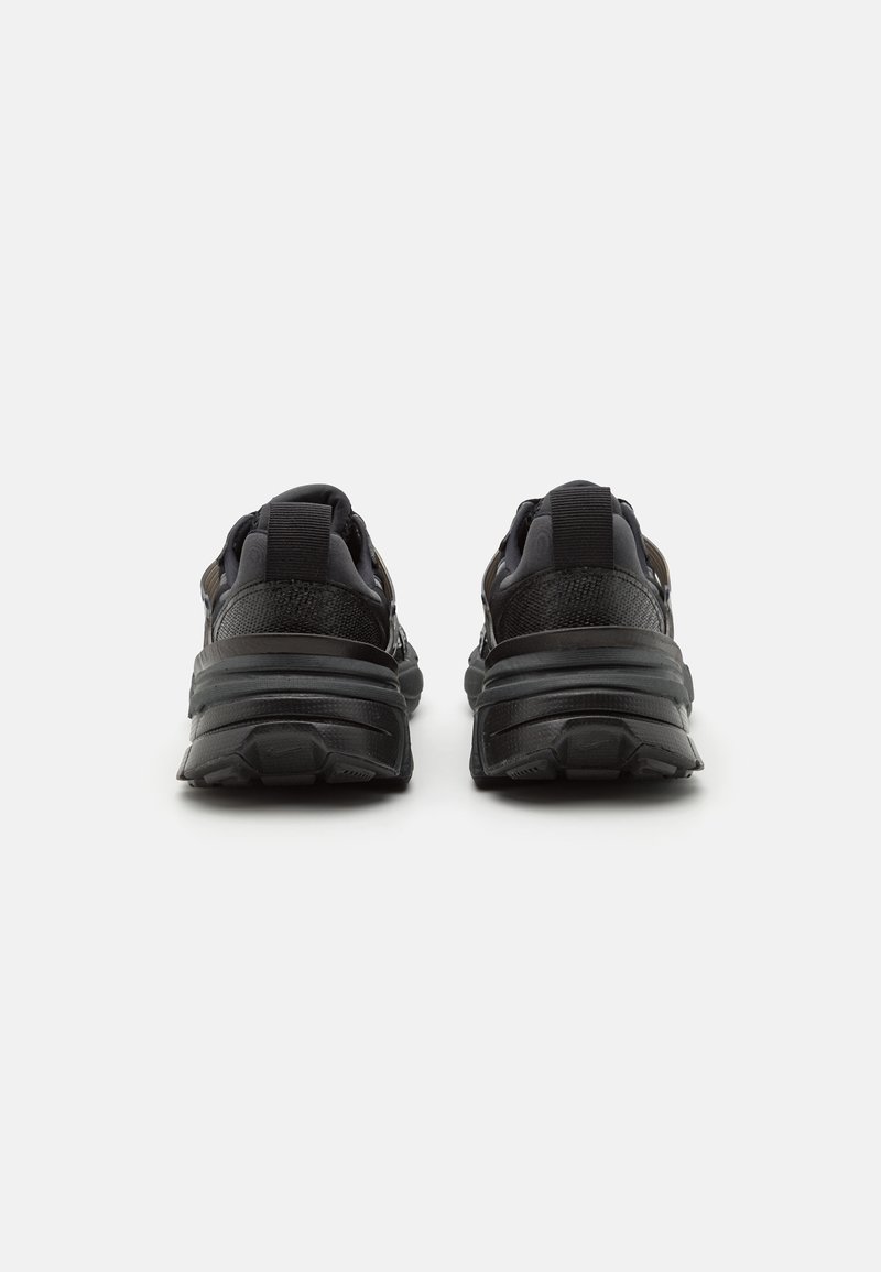 Chaussures de sport noires avec une tige en maille texturée, semelle rembourrée et bande de roulement en caoutchouc prononcée. Elles disposent de doubles sangles pour un ajustement sécurisé.