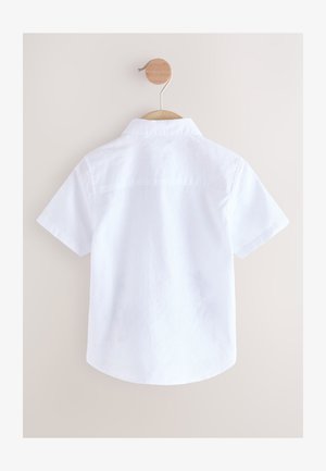 Rövid ujjú, fehér gombos ing galléros nyakkal, hátsó vállrésszel és lekerekített szegéllyel, fa fogason kiállítva.