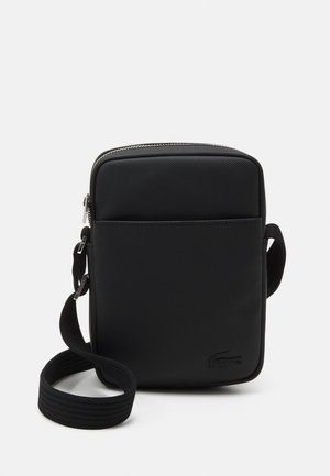 Čierna obdĺžniková crossbody taška vyrobená z textúrovaného materiálu. Obsahuje horný zips, nastaviteľný popruh a logo vtlačené na prednej strane.