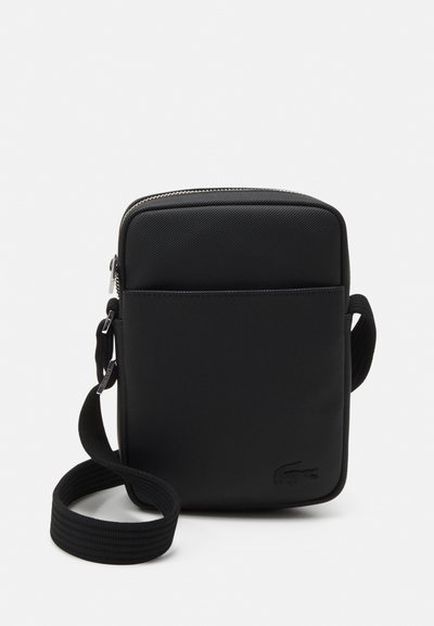 Sac bandoulière rectangulaire noir en matériau texturé. Il dispose d'une fermeture éclair supérieure, d'une sangle ajustable et d'un logo embossé à l'avant.