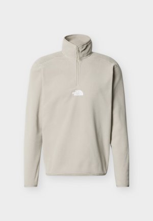 Šviesiai smėlio spalvos vilnos megztinis su ilgomis rankovėmis, ketvirčio užtrauktuku, aukštu apykakliu ir balta „The North Face“ logotipu ant krūtinės.