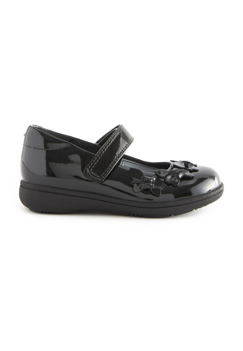 Zapato Mary Jane de charol negro con una correa de Velcro, punta redonda y adornos florales en la parte frontal, presenta una suela plana de goma.