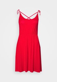 Robe rouge sans manches avec bretelles à nouer, présentant un corsage ajusté et une jupe fluide. Tissu doux avec une texture lisse. Détail de bretelles croisées.