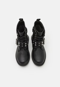 Botas negras hasta el tobillo hechas de cuero texturizado, con diseño de cordones, correa con tachuelas y cremallera lateral para un uso fácil.
