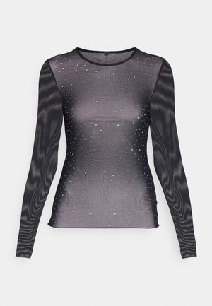 Svart langermet topp laget av gjennomsiktig stoff, dekorert med rhinestones ordnet i et gradientmønster fra tett til spredt over brystet.