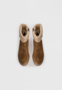 Botas de tobillo de ante marrón con un suave puño de felpa beige. Presentan una cremallera lateral y una suela texturizada para mayor agarre. Diseño simple y funcional.