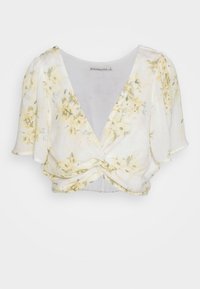 Blusa floral com um design envolvente, mangas curtas e esvoaçantes, e um frente torcido. As cores incluem amarelo suave e branco, com uma textura subtil.
