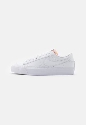 Witte leren sneakers met een laag model, platte rubberen zool en een ronde neus. Heeft een klassiek vetersysteem en subtiele branding aan de zijkant.