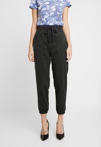 Ciemnoszare spodnie dresowe z elastycznymi mankietami i sznurkiem w pasie, z dwoma przednimi kieszeniami i miękkim, teksturowanym materiałem.