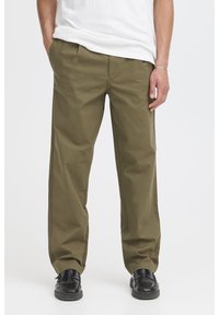 Olivengrønne, lige bukser i en holdbar bomuldsblanding med sidelommer og en glat tekstur, parret med sorte sko.