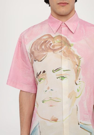 Camisa de botones de manga corta en tela rosa que presenta un gran retrato en acuarela de una persona, con texturas suaves y contornos delicados.