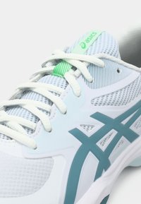 Sportieve schoen in lichtblauw en wit mesh, met turquoise accenten, opvallende veters en een groen logo op de tong.