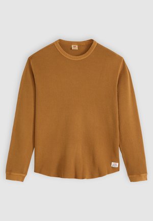 Pikad varrukad, sinepikollane termalpoliis, millel on tekstuurne ribikujundus, ümmargune kaelus ja väike brändi sildike alumises servas.