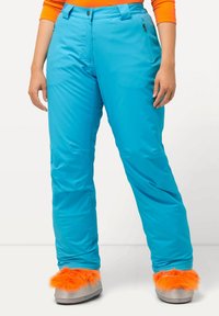 Turquoise sneeuwbroeken met een gladde textuur, middelhoge taille en ritszakken. Gecombineerd met grijze slippers met feloranje fuzzy accenten.