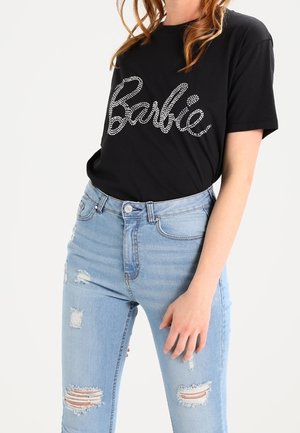 Musta T-paita, jossa on strassikivillä varustettu "Barbie" logo, yhdistettynä vaaleansinisii revittyihin farkkuihin. Asu on rento muotoilu ja väljä istuvuus.