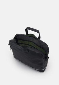 Zwarte synthetische tas met een ritsluiting, twee handvatten en een olijfgroene binnenkant; heeft compartimenten voor organisatie.