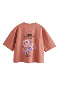 Camiseta coral de manga corta con un estampado gráfico de pasteles y texto que dice "Flavio's Breakfast Club". Material de algodón suave, corte relajado.
