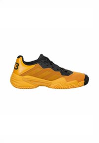 Orangenes Sportschuh mit schwarzen Akzenten, strukturiertem Mesh-Oberteil, Gummisohle und drei diagonalen Streifen an der Seite. Enthält eine auffällige Zahl an der Ferse.