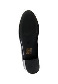 Semelle de chaussure noire avec une étiquette de taille 37 et des symboles indiquant les matériaux, dont le cuir et le synthétique, sur fond blanc.