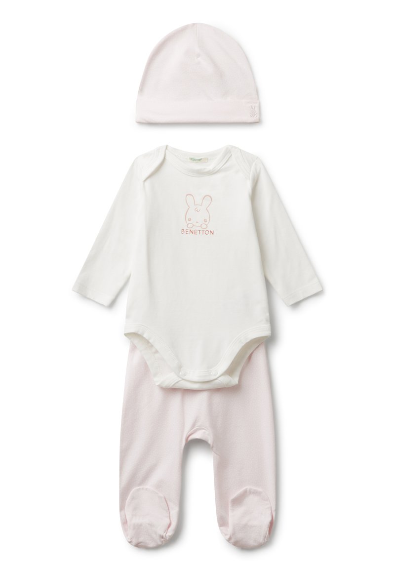 Měkká růžová dětská čepice, bílý body s dlouhým rukávem s grafikou králíka a textem "Benetton", a měkké růžové kalhoty se špičkami.
