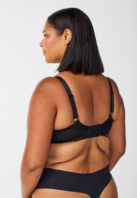 Schwarzer BH aus glattem Stoff mit verstellbaren Trägern, Haken- und Ösenverschluss auf der Rückseite und nahtlosem Design zur Verbesserung des Tragekomforts.