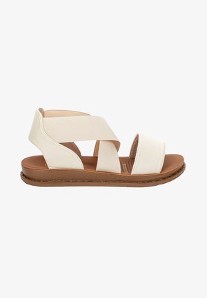 Białe skórzane sandały z skrzyżowanymi elastycznymi paskami, miękką brązową wkładką i płaską podeszwą; minimalistyczny design odpowiedni do codziennego noszenia.