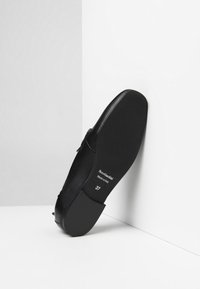 Scarpa in pelle nera con punta rotonda e suola piatta, con una superficie liscia. Taglia 37 e dettagli del marchio visibili sulla suola.